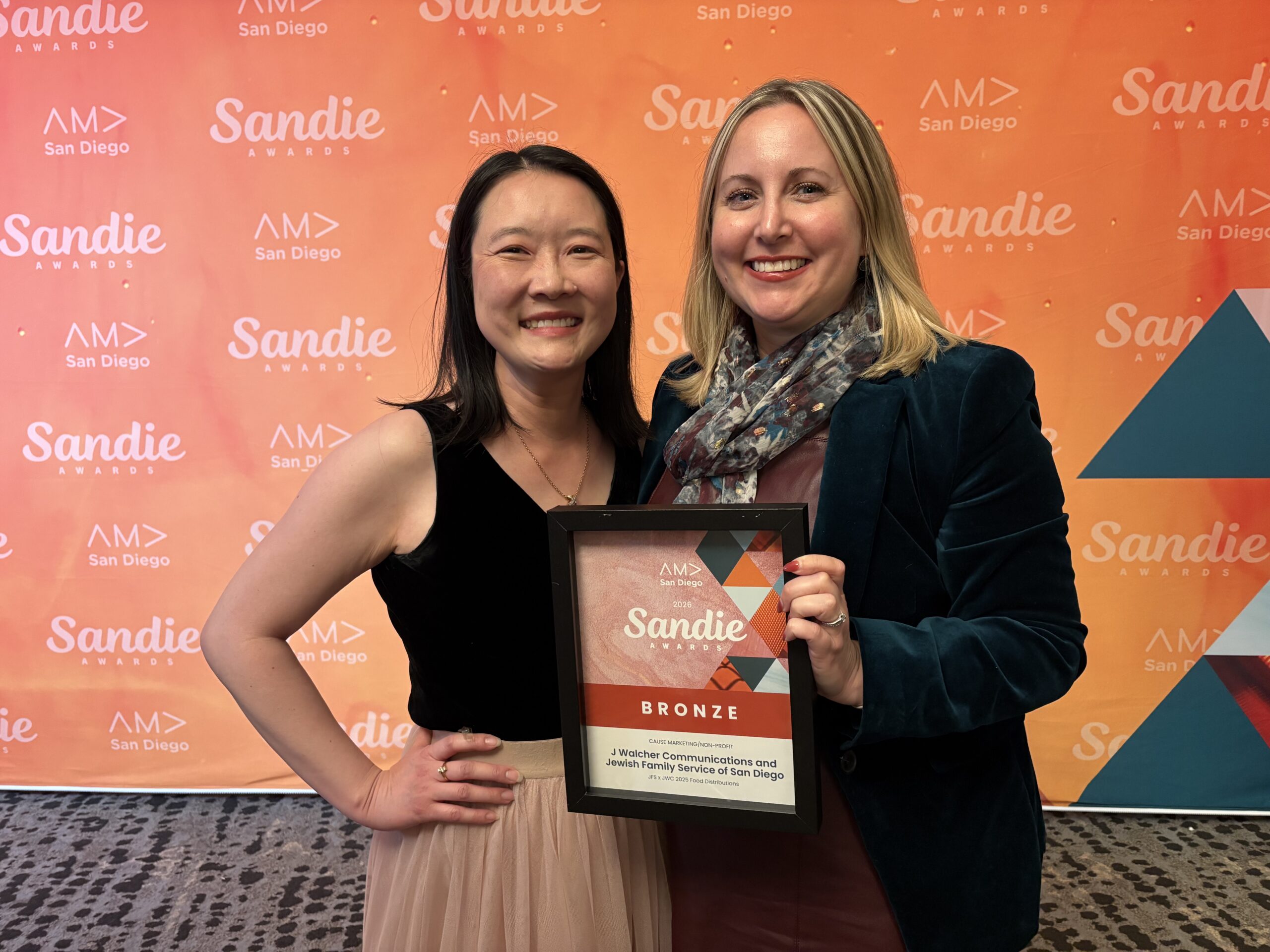 Sandy Young and Molly Pincherli hold the AMA Sandie award in front of an orange background